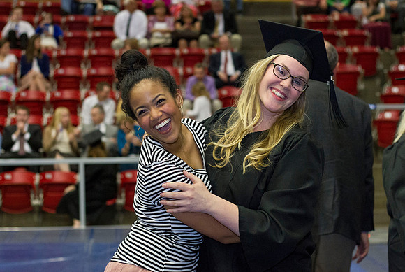 A 2014 Winter graduate celebrates with her friend before Convocation in the Hart Auditorium.