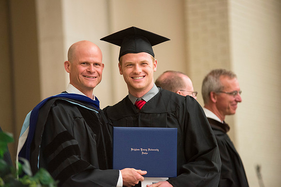 Graduate poses with Eric D. Karl, the dean of The College of Physical Sciences and Engineering.