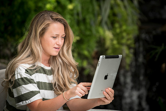 Katelyn Crompton studies in the Benson Greenhouse using her iPad.