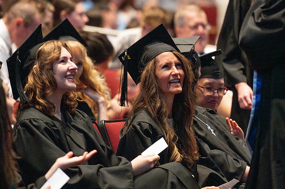 Brother Timothy Rarick laughs with graduates during convocation for the College of Education & Human Development