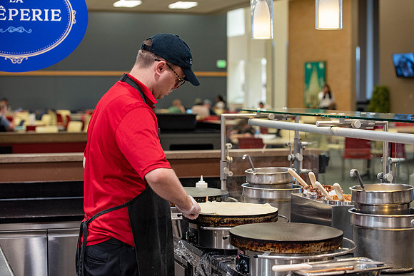 Student employee makes and serves Crepes in the Food Courts, for La Creperie