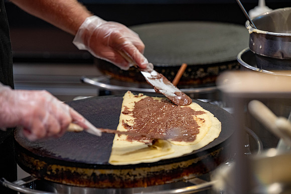 Student employee makes and serves Crepes in the Food Courts, for La Creperie