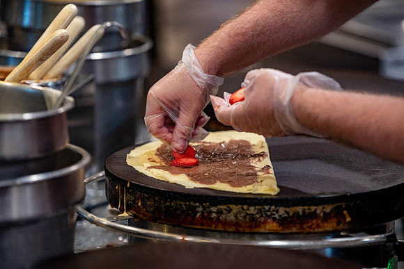 Student employee makes and serves Crepes in the Food Courts, for La Creperie