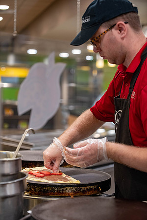 Student employee makes and serves Crepes in the Food Courts, for La Creperie