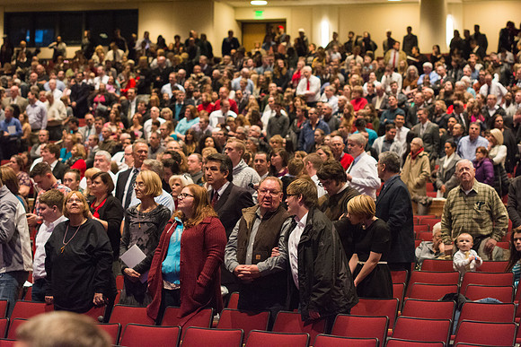 Family and friends of the graduates stand as the graduates enter during Processional.