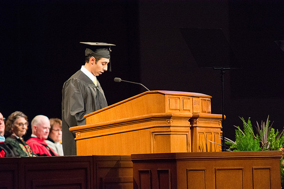 A graduate reads a scripture during Commencement.