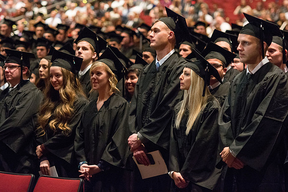 Graduates stand as President Clark G. Gilbert pronounces them as graduates.