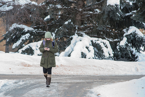 Student distracts her mind from the cold and listens to music on the way home.