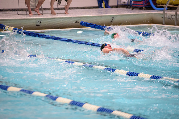 Students of varying swim teams compete in different swimming events.