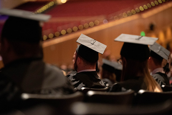 Students partipate in walking to graduate from the College of Business and Communication.