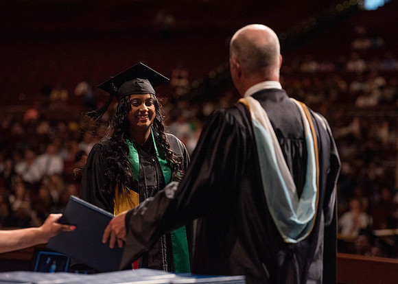 Students partipate in walking to graduate from the College of Business and Communication.