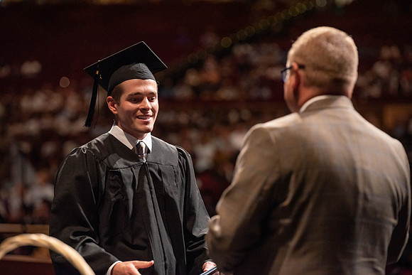Students partipate in walking to graduate from the College of Business and Communication.