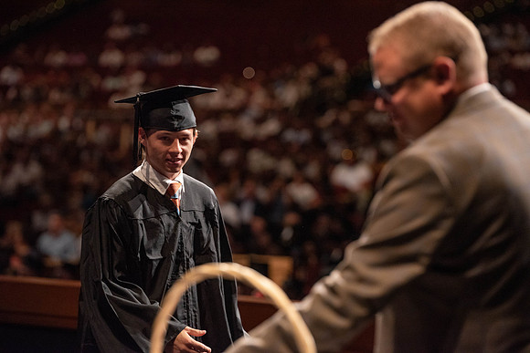 Students partipate in walking to graduate from the College of Business and Communication.
