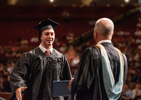 Students partipate in walking to graduate from the College of Business and Communication.