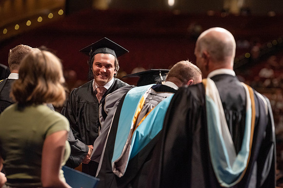 Students partipate in walking to graduate from the College of Business and Communication.