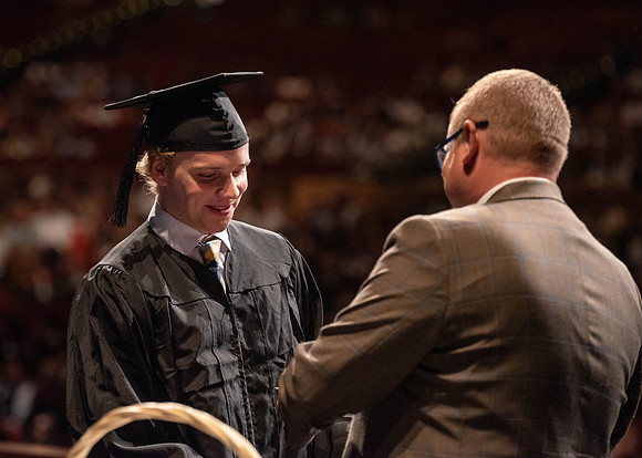 Students partipate in walking to graduate from the College of Business and Communication.