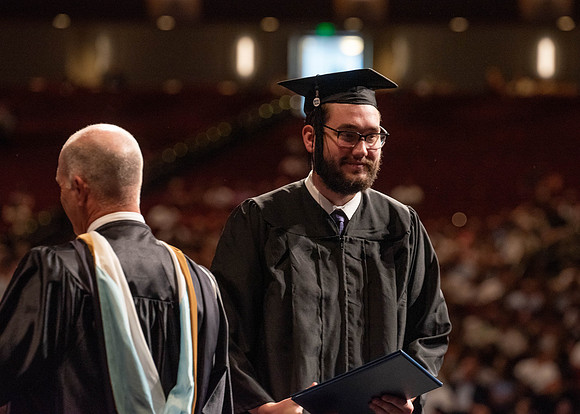 Students partipate in walking to graduate from the College of Business and Communication.