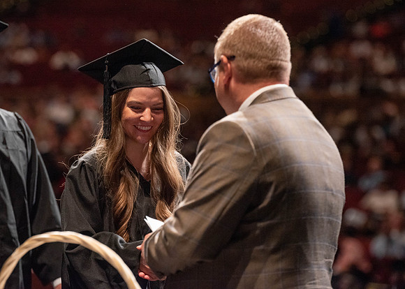 Students partipate in walking to graduate from the College of Business and Communication.