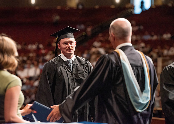 Students partipate in walking to graduate from the College of Business and Communication.