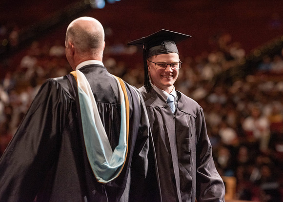 Students partipate in walking to graduate from the College of Business and Communication.