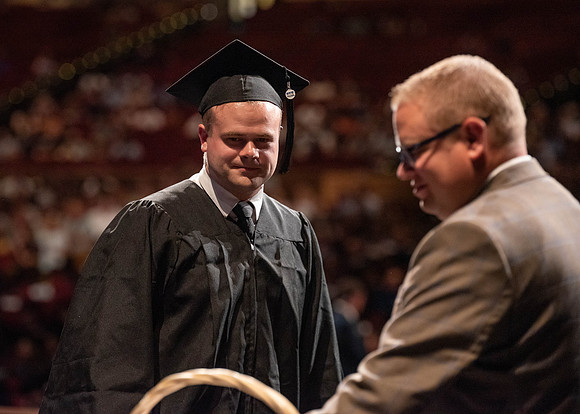 Students partipate in walking to graduate from the College of Business and Communication.
