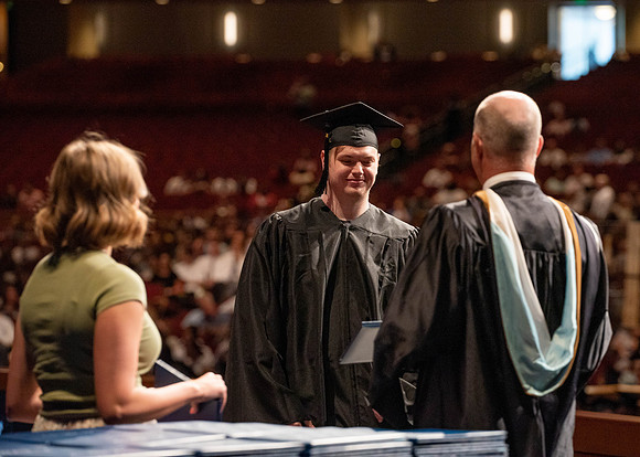 Students partipate in walking to graduate from the College of Business and Communication.