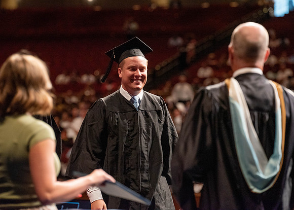 Students partipate in walking to graduate from the College of Business and Communication.