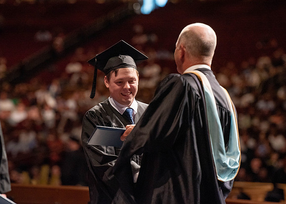 Students partipate in walking to graduate from the College of Business and Communication.