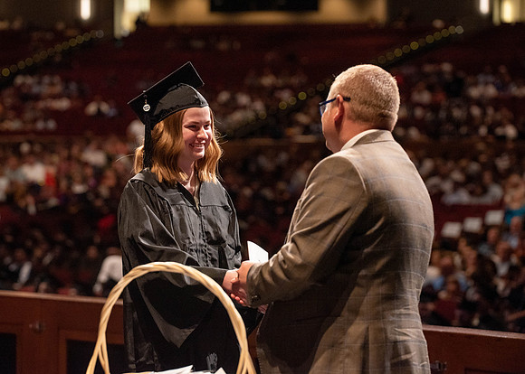 Students partipate in walking to graduate from the College of Business and Communication.