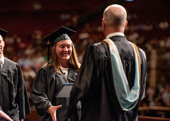 Students partipate in walking to graduate from the College of Business and Communication.