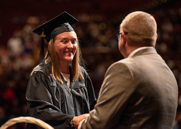 Students partipate in walking to graduate from the College of Business and Communication.
