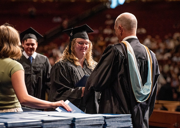 Students partipate in walking to graduate from the College of Business and Communication.