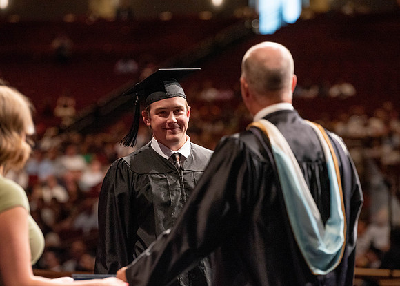 Students partipate in walking to graduate from the College of Business and Communication.