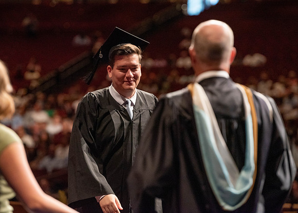 Students partipate in walking to graduate from the College of Business and Communication.