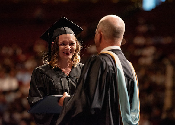 Students partipate in walking to graduate from the College of Business and Communication.
