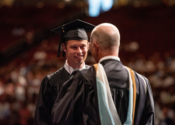 Students partipate in walking to graduate from the College of Business and Communication.