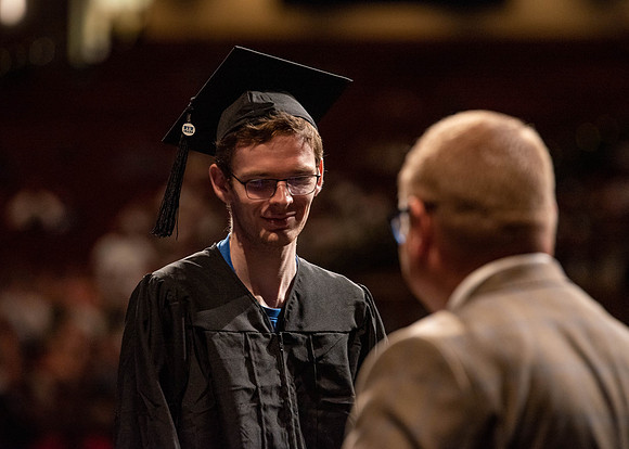 Students partipate in walking to graduate from the College of Business and Communication.
