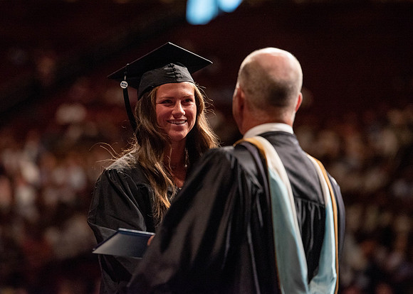 Students partipate in walking to graduate from the College of Business and Communication.