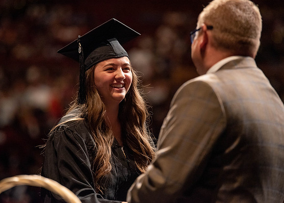 Students partipate in walking to graduate from the College of Business and Communication.