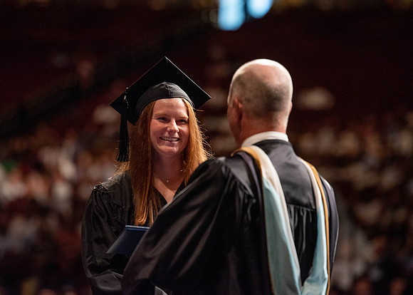 Students partipate in walking to graduate from the College of Business and Communication.