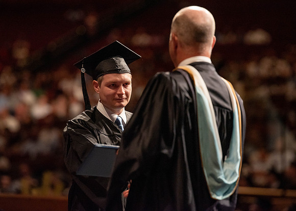 Students partipate in walking to graduate from the College of Business and Communication.
