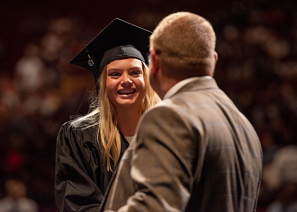 Students partipate in walking to graduate from the College of Business and Communication.