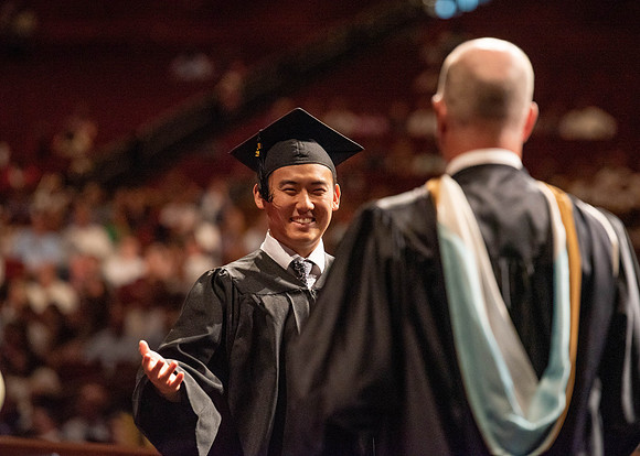 Students partipate in walking to graduate from the College of Business and Communication.