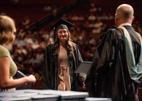 Students partipate in walking to graduate from the College of Business and Communication.