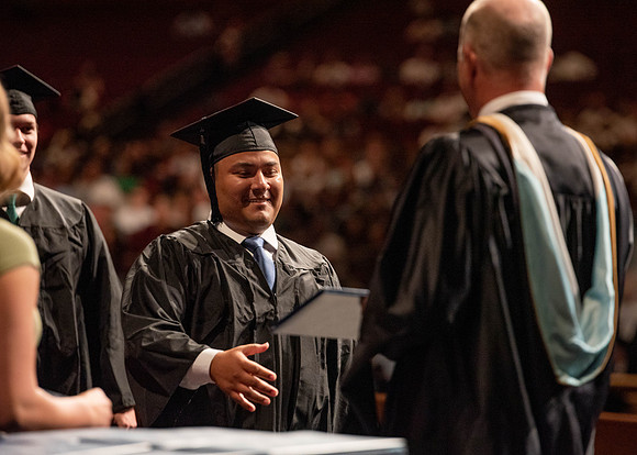 Students partipate in walking to graduate from the College of Business and Communication.