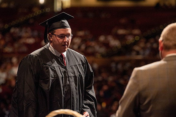 Students partipate in walking to graduate from the College of Business and Communication.