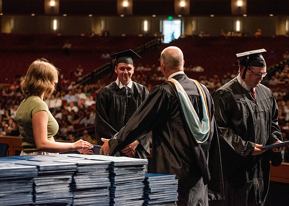 Students partipate in walking to graduate from the College of Business and Communication.