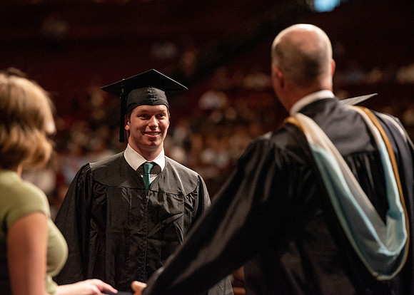 Students partipate in walking to graduate from the College of Business and Communication.