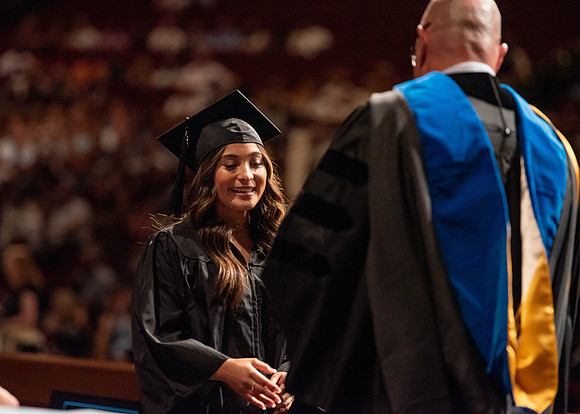 Students partipate in walking to graduate from the College of Business and Communication.