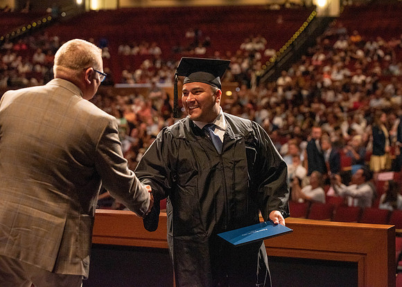 Students partipate in walking to graduate from the College of Business and Communication.